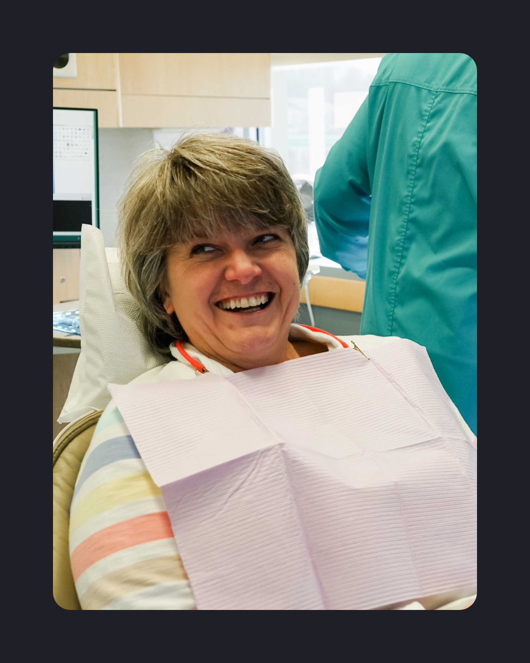 Patient smiling and laughing while seated in a dental chair during a dental appointment.